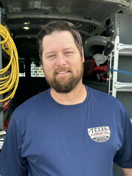 Andy Fauver in a Texan Plumbing Pros shirt in front of the service van